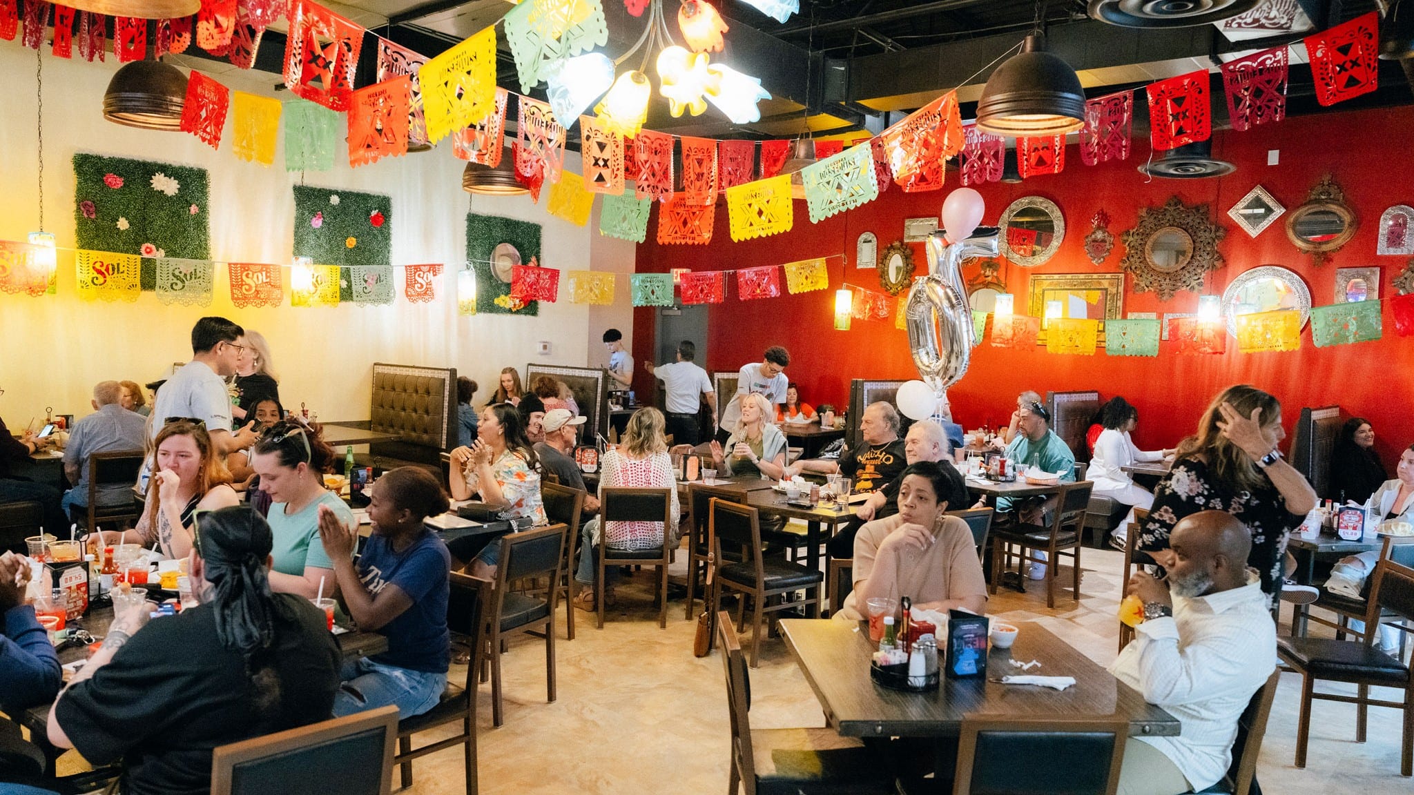 A full dining room at La Tolteca under colorful papel picado